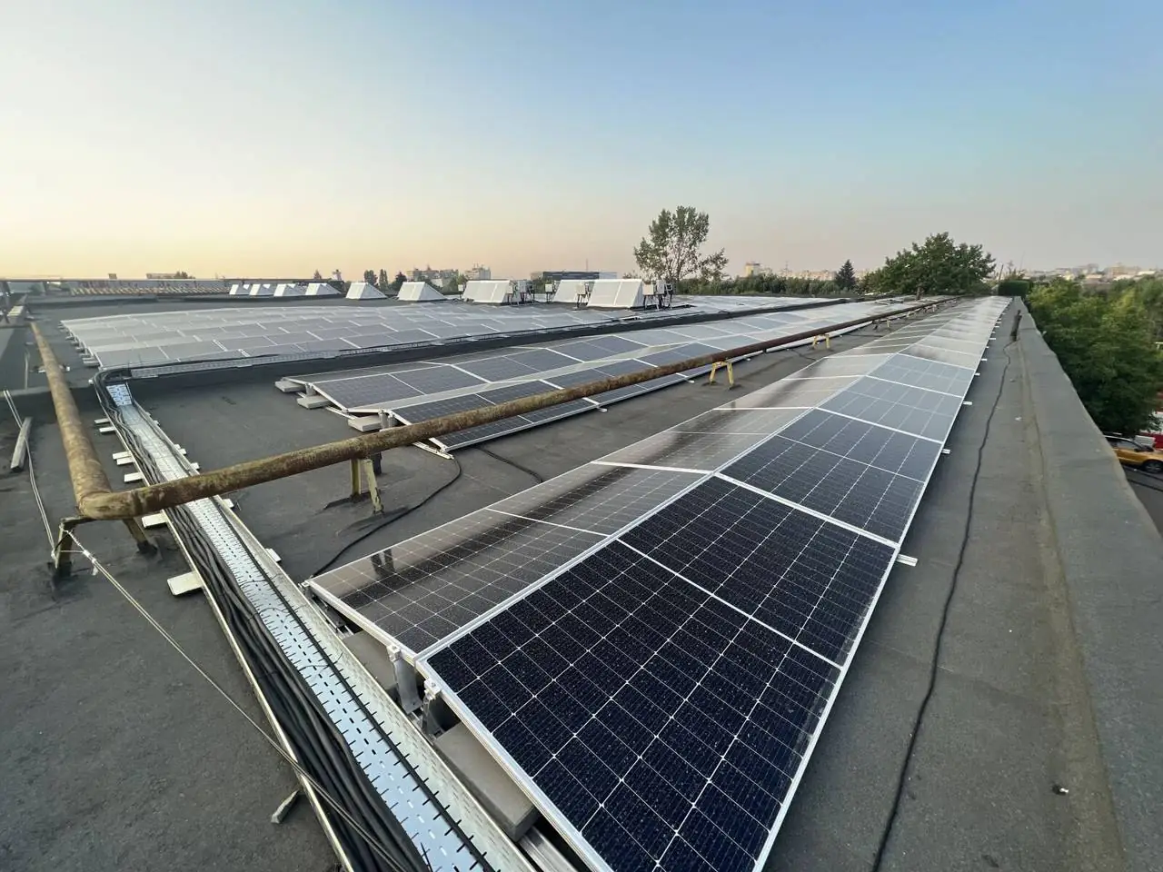 Cale de cabluri și panouri fotovoltaice montate pe acoperișul unei hale industriale
